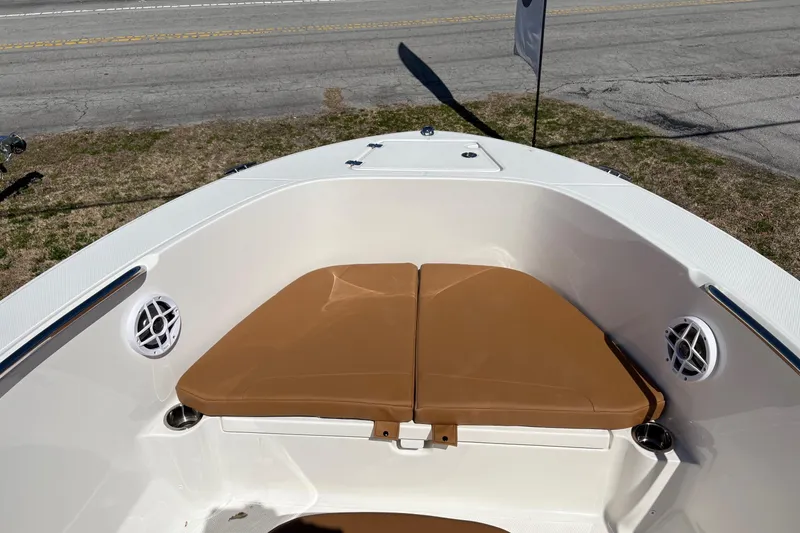 Slide: The Image of 2026 Robalo R180 Center Console boat with tan seating and speakers, parked near a road. - 6