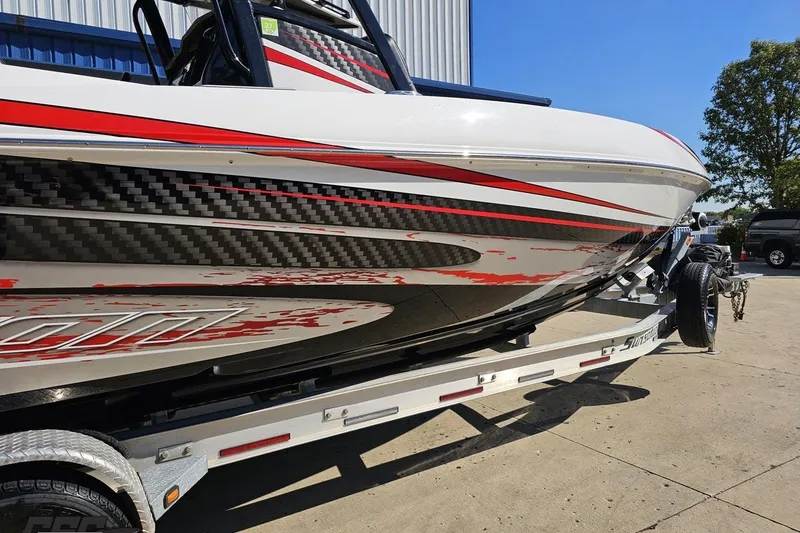 Slide: The Image of 2020 Sunsation 32 CCX boat with sleek red and black graphics on a trailer. - 12