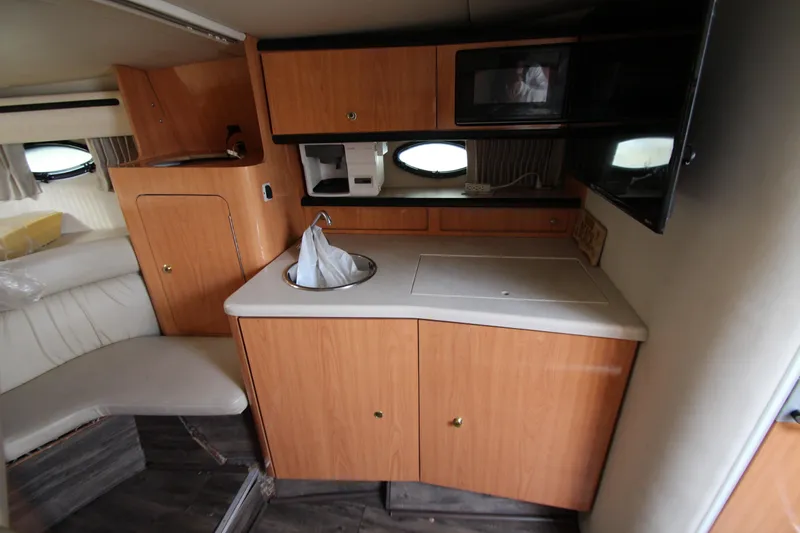 Slide: The Image of 1999 Regal Commodore 322 boat interior with kitchenette, sink, and microwave. - 12