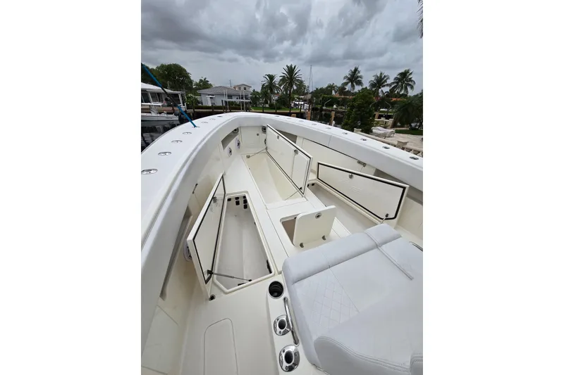 Slide: The Image of 2019 SeaVee 390Z boat interior with open storage compartments and seating under cloudy skies. - 4