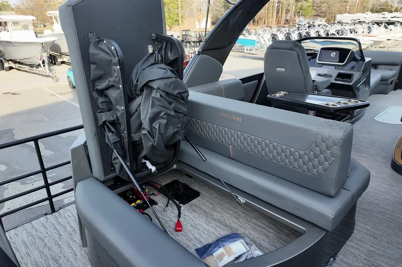 Slide: The Image of 2026 Sylvan M-5 CLZ DC boat interior with storage compartment open, showcasing seating and console. - 17