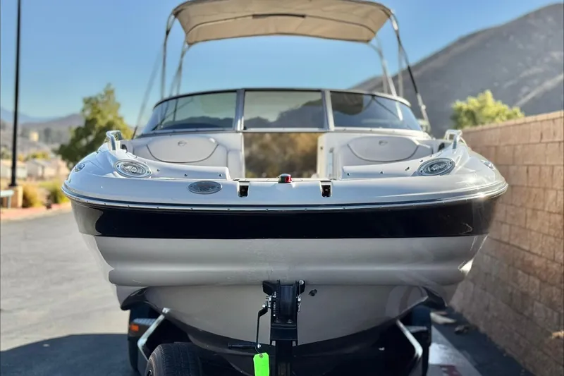 Slide: The Image of 2006 Crownline 260 EX boat on trailer, parked outdoors with mountains in background. - 2