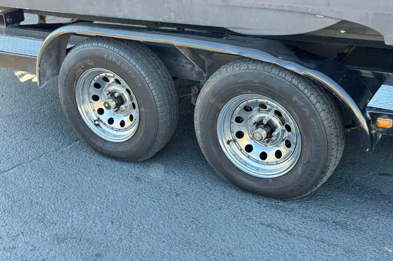Slide: The Image of Trailer wheels of a 2006 Crownline 260 EX boat on asphalt surface. - 32