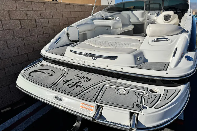 Slide: The Image of 2006 Crownline 260 EX boat with "Enjoy Life" text on the deck, parked near a wall. - 6