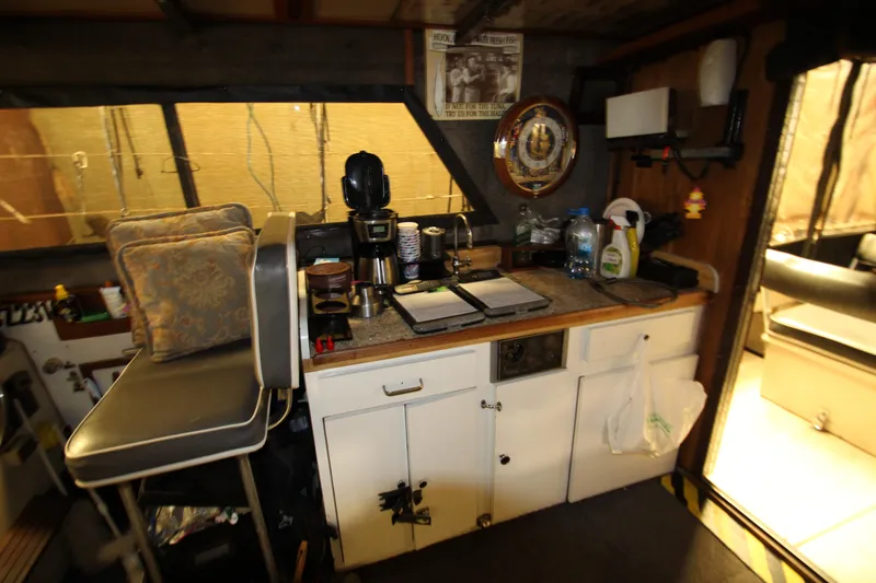 Slide: The Image of Interior of 1980 Delta Boatworks 34 Offshore, featuring a compact kitchen area with seating. - 24