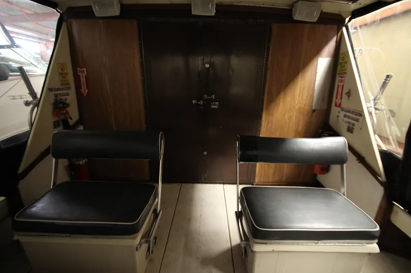 Slide: The Image of Interior of 1980 Delta Boatworks 34 Offshore with two black cushioned seats. - 7
