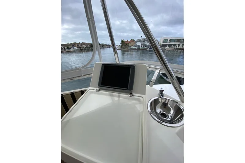 Slide: The Image of Helm of 2012 Mikelson 43 Sportfisher with navigation screen and sink, overlooking marina. - 18