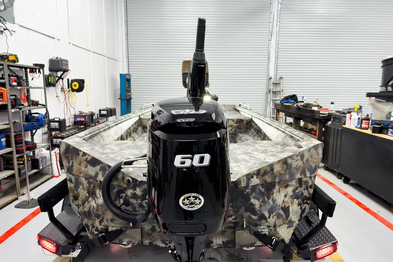 Slide: The Image of Camouflage-patterned 2026 Excel Eclipse boat with a 60 HP motor in a workshop setting. - 12