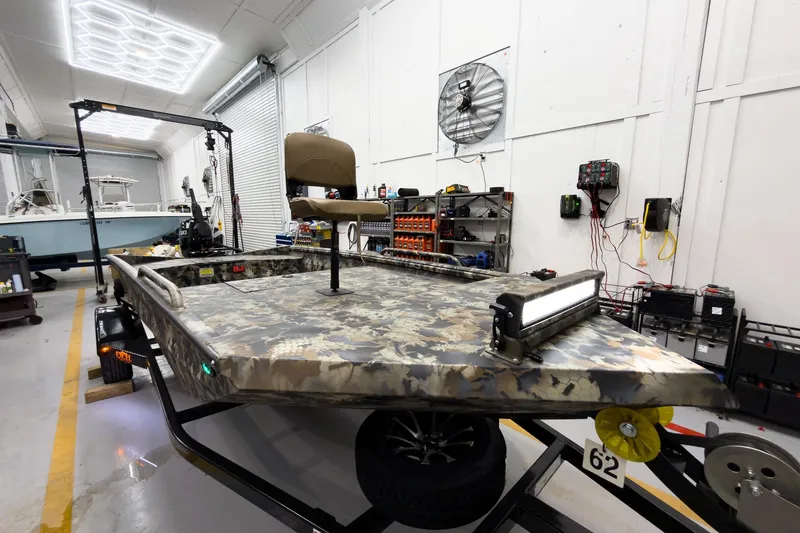 Slide: The Image of 2026 Excel Eclipse boat in workshop, featuring camouflage design and mounted seat. - 17