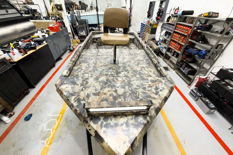 Slide: The Image of Camouflage-patterned Excel Eclipse 2026 boat in a workshop with tools and equipment. - 18