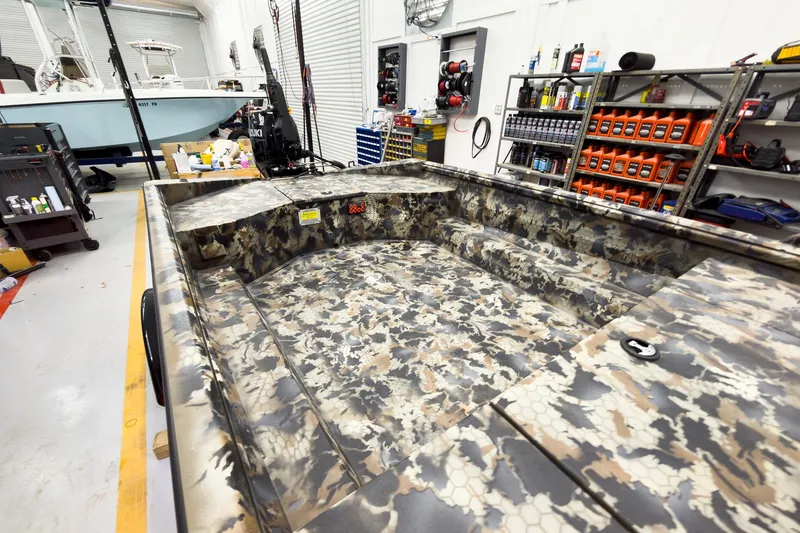 Slide: The Image of Camouflage-patterned interior of a 2026 Excel Eclipse boat in a workshop setting. - 19