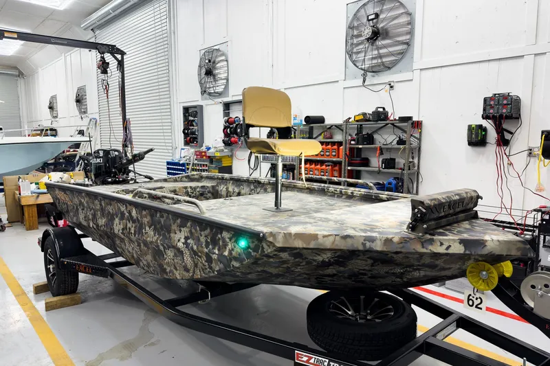 The Image of 2026 Excel Eclipse boat in workshop, camouflage design, mounted on trailer. - 2