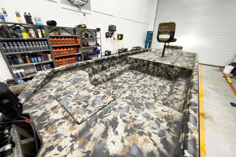 Slide: The Image of Camouflage-patterned 2026 Excel Eclipse boat in a workshop with shelves of supplies. - 20