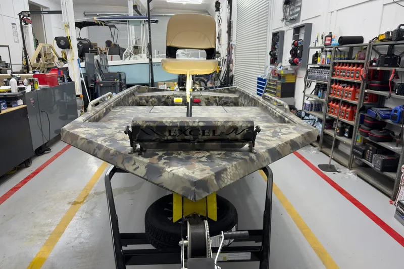 Slide: The Image of 2026 Excel Eclipse boat in workshop, camouflage design, surrounded by tools and equipment. - 3