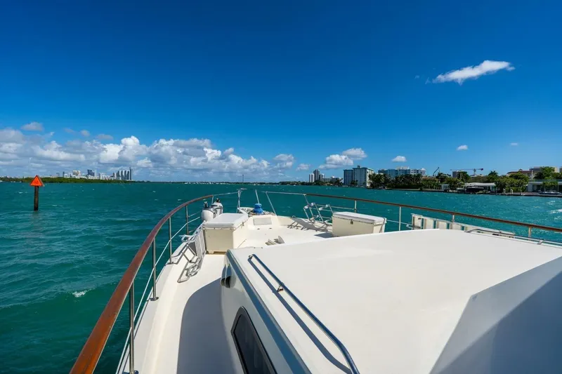 Slide: The Image of 1978 Hatteras 53 Yacht Fisherman cruising on a sunny day with city skyline in the background. - 17