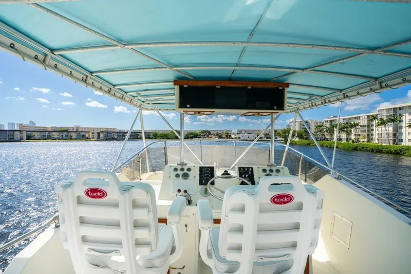 Slide: The Image of 1978 Hatteras 53 Yacht Fisherman helm with blue canopy, overlooking waterfront buildings. - 21