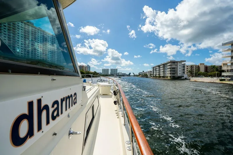 Slide: The Image of 1978 Hatteras 53 Yacht Fisherman cruising through a scenic urban waterway. - 27