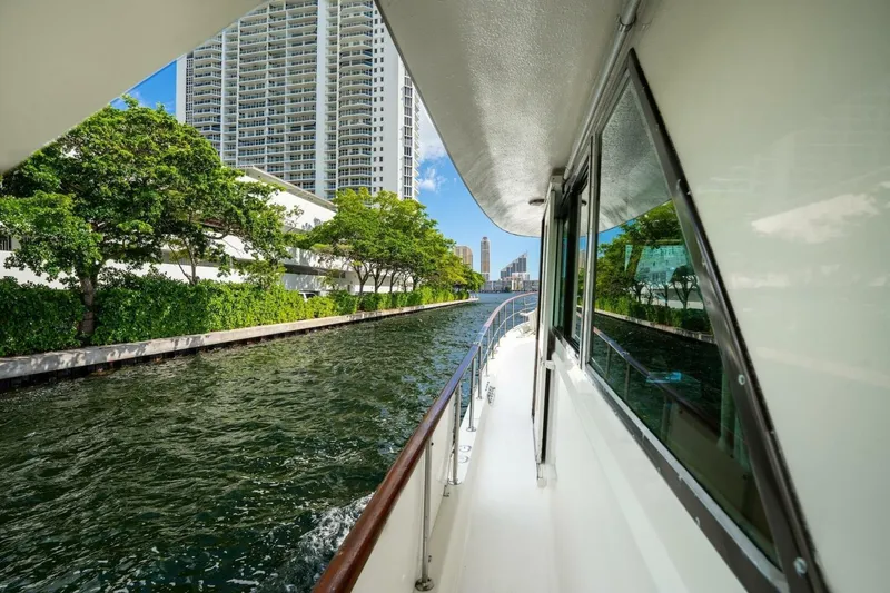 Slide: The Image of 1978 Hatteras 53 Yacht Fisherman cruising along a scenic urban waterway. - 28