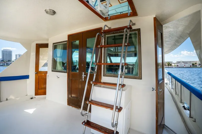 Slide: The Image of 1978 Hatteras 53 Yacht Fisherman deck with wooden doors and ladder, overlooking waterfront. - 32