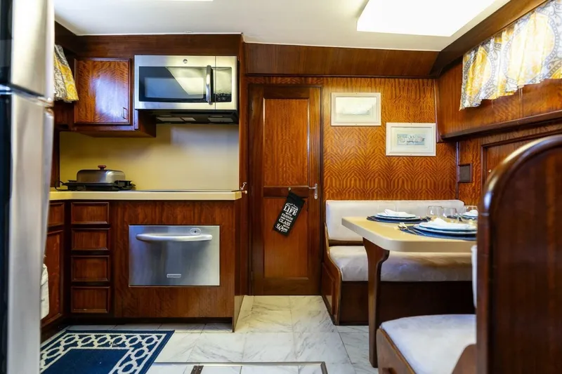 Slide: The Image of 1978 Hatteras 53 Yacht Fisherman interior with kitchen and dining area, featuring wood cabinetry. - 63