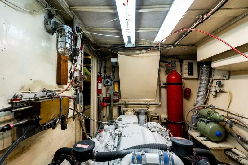 Slide: The Image of Engine room of a 1978 Hatteras 53 Yacht Fisherman, featuring mechanical equipment and fire extinguisher. - 78