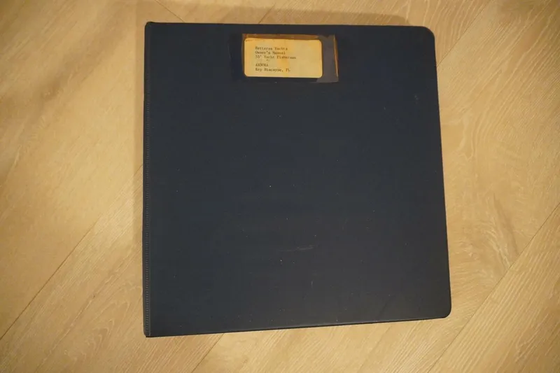 Slide: The Image of Black binder labeled "Hatteras 53 Yacht Fisherman 1978" on wooden floor. - 87