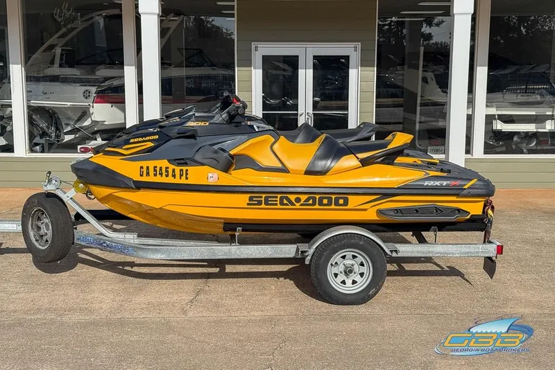 The Image of 2021 Sea-Doo RXT-X 300 jet ski on trailer, parked outside a showroom. - 1