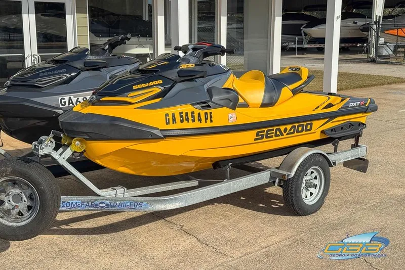 Slide: The Image of 2021 Sea-Doo RXT-X 300 jet ski in yellow on a trailer, parked outdoors. - 3