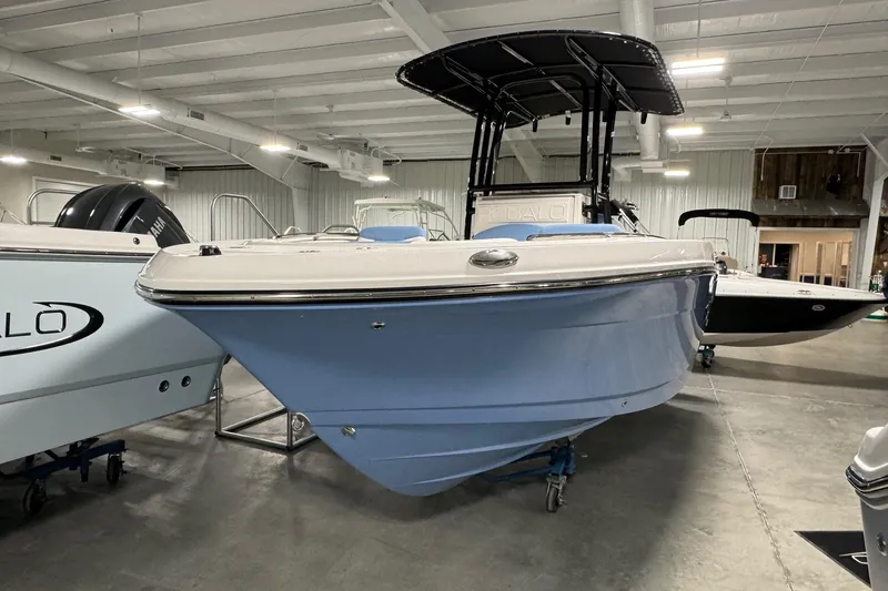 Slide: The Image of 2026 Robalo R202 Explorer boat in showroom, featuring sleek blue hull and modern design. - 2