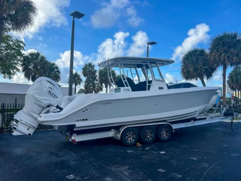 Slide: The Image of 2025 Edgewater 340CC boat on trailer, parked outdoors under a blue sky. - 2