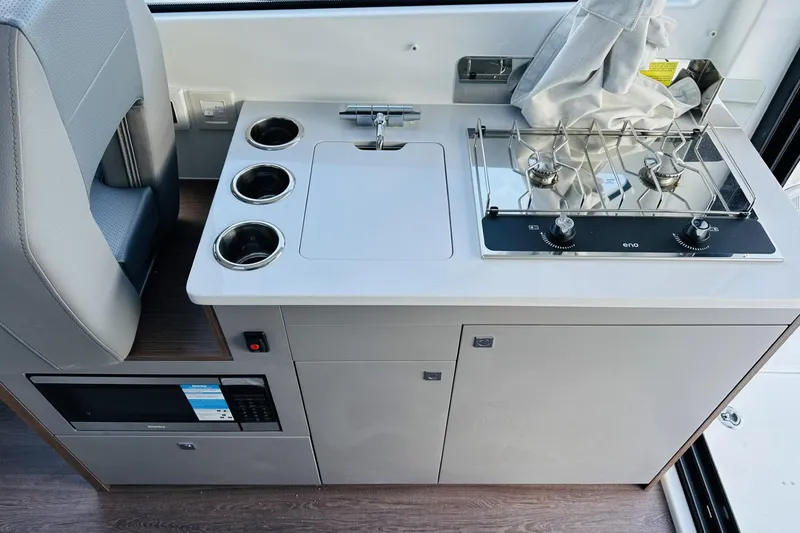 Slide: The Image of 2026 Beneteau Antares 9 V2 boat kitchen with stove, sink, and storage. - 13