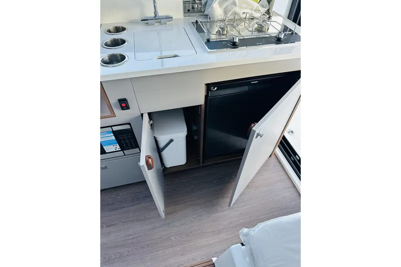 Slide: The Image of 2026 Beneteau Antares 9 V2 kitchen area with sink, stove, and storage cabinets. - 19
