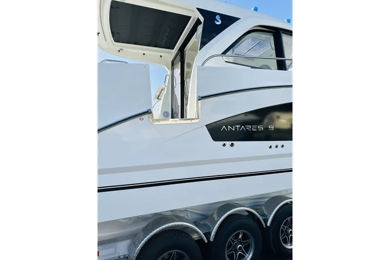 Slide: The Image of 2026 Beneteau Antares 9 V2 boat side view with open door and trailer wheels. - 3