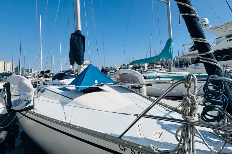 Slide: The Image of 1989 Hunter Legend 37 sailboat docked in a marina with modern buildings in the background. - 8