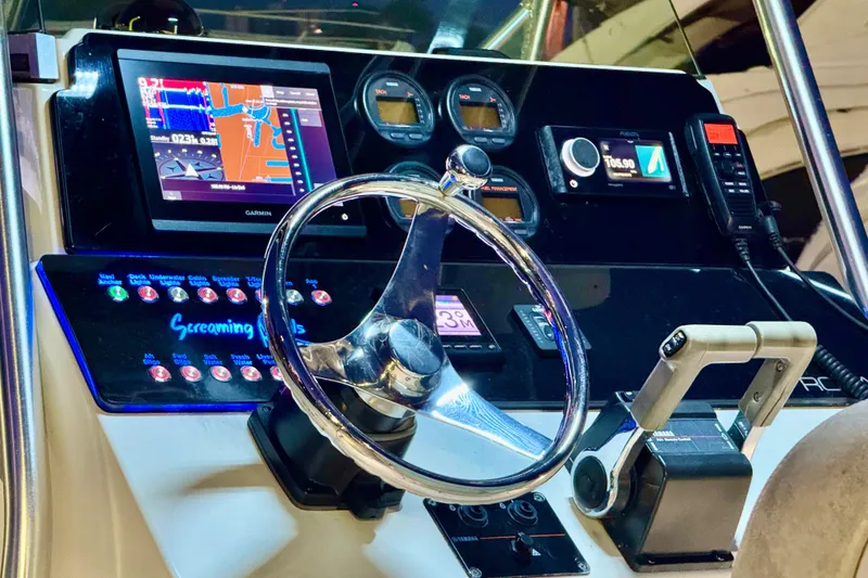 Slide: The Image of 2004 Robalo R260 Center Console boat with T-top, parked in marina under clear blue sky. - 12