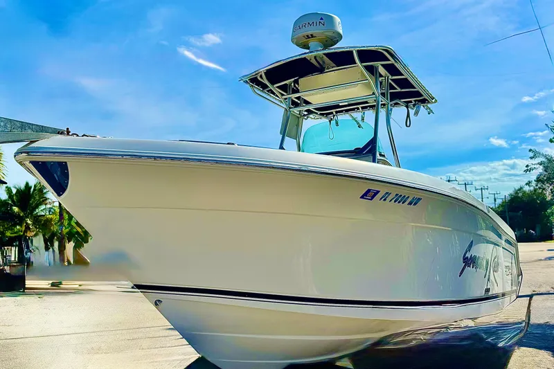 Slide: The Image of 2004 Robalo R260 Center Console boat with steering wheel and control panel, docked under blue sky. - 30