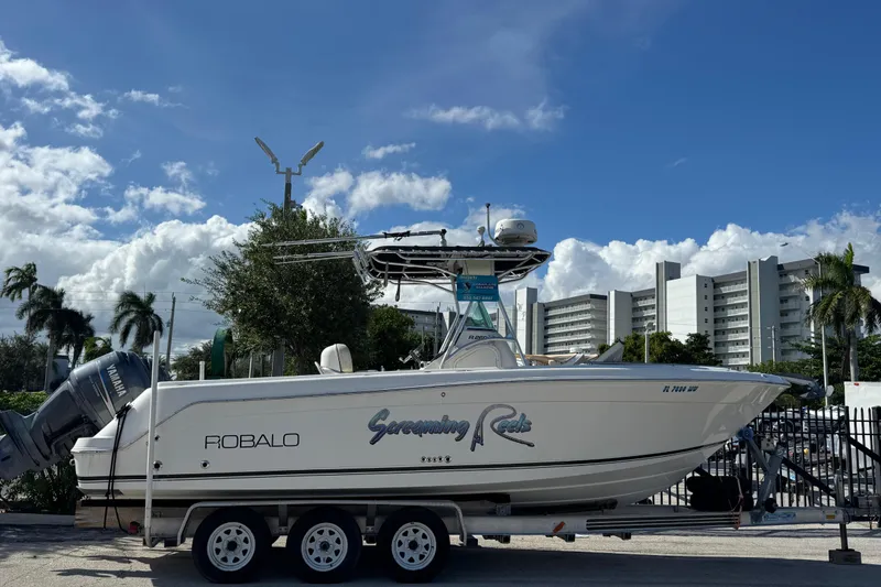 Slide: The Image of 2004 Robalo R260 Center Console boat with American flags, under a cloudy sky. - 34