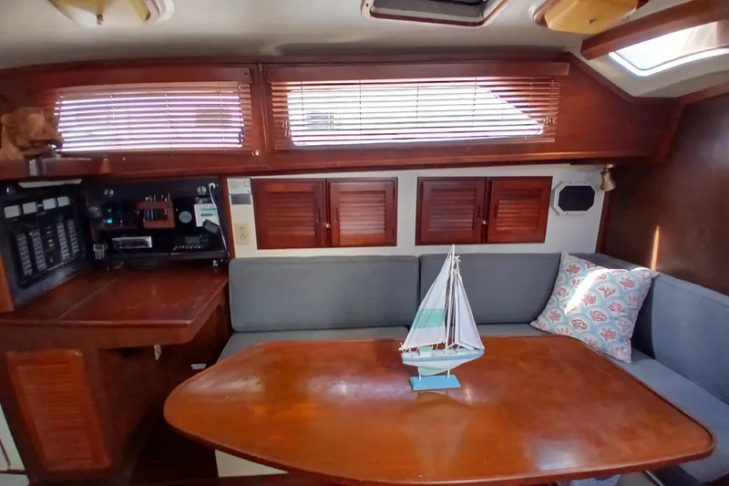 Slide: The Image of Cozy 1986 Irwin 43 yacht interior with wooden table, model sailboat, and cushioned seating. - 10