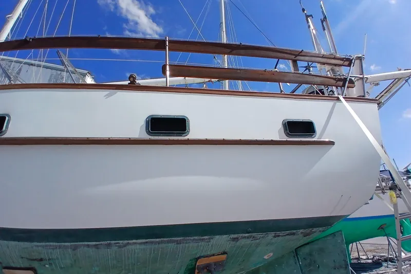 Slide: The Image of 1986 Irwin 43 sailboat on land, showcasing hull and deck details under a clear blue sky. - 3