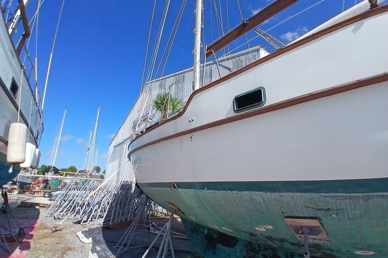 Slide: The Image of 1986 Irwin 43 sailboat on dry dock, surrounded by other boats under a clear blue sky. - 4