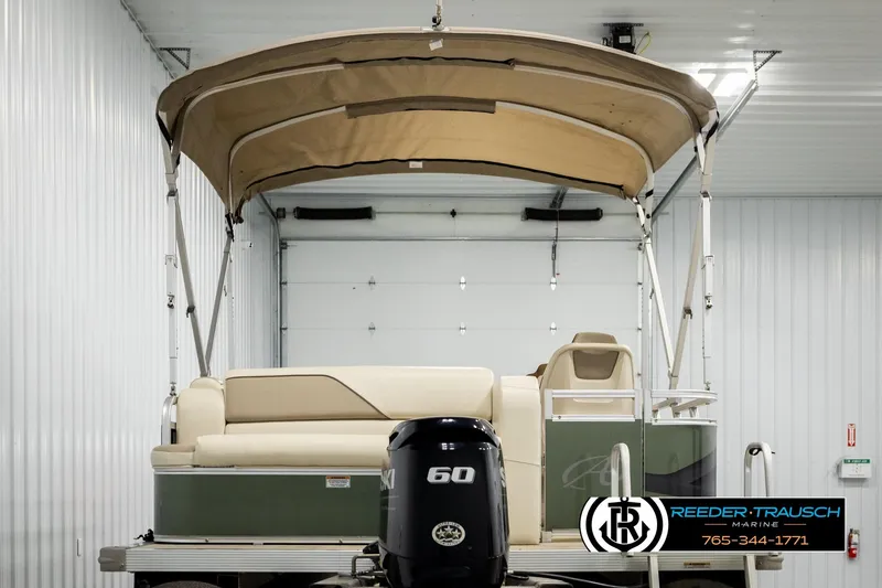 Slide: The Image of 2023 Avalon VEN BF boat with canopy in a garage, featuring a 60 HP Suzuki motor. - 7