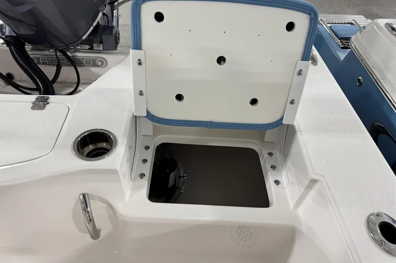 Slide: The Image of 2026 Robalo 206 Cayman boat storage compartment with open lid and cup holder. - 10