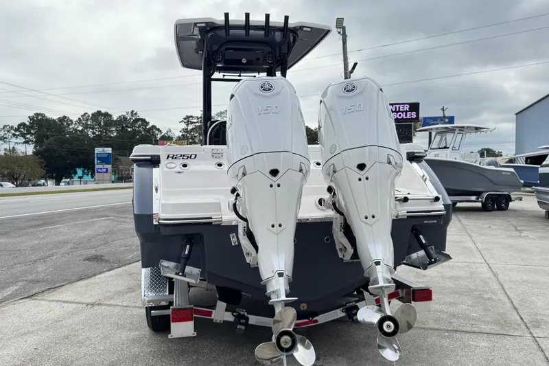 Slide: The Image of 2026 Robalo R250 Center Console boat with dual outboard engines, parked on a concrete surface. - 2