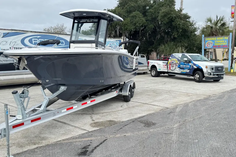 Slide: The Image of 2026 Robalo R250 Center Console boat on trailer, parked near a transport service truck. - 36