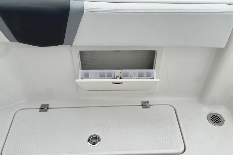 Slide: The Image of 2026 Robalo R250 Center Console storage compartment with tackle box and drain. - 8