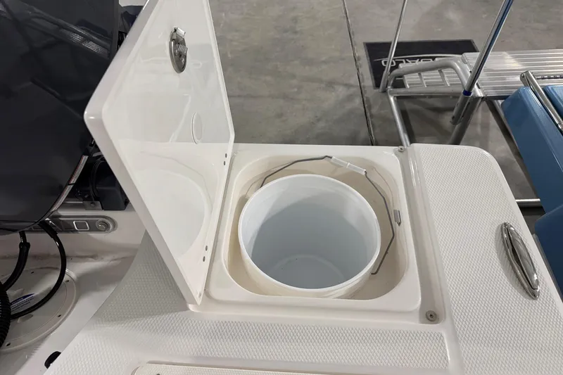 Slide: The Image of Open storage compartment on 2026 Robalo 206 Cayman boat, featuring a white bucket inside. - 11