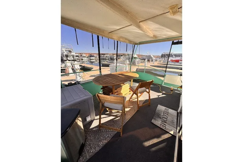 Slide: The Image of 1984 Boatel Hercules boat deck with wooden table, chairs, and marina view. - 14