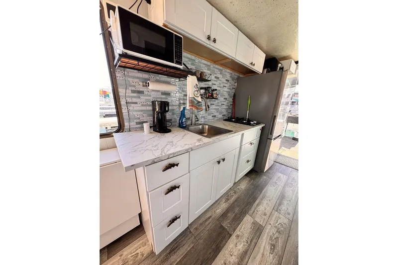 Slide: The Image of Modern kitchen in 1984 Boatel Hercules with white cabinets, marble countertop, and appliances. - 17