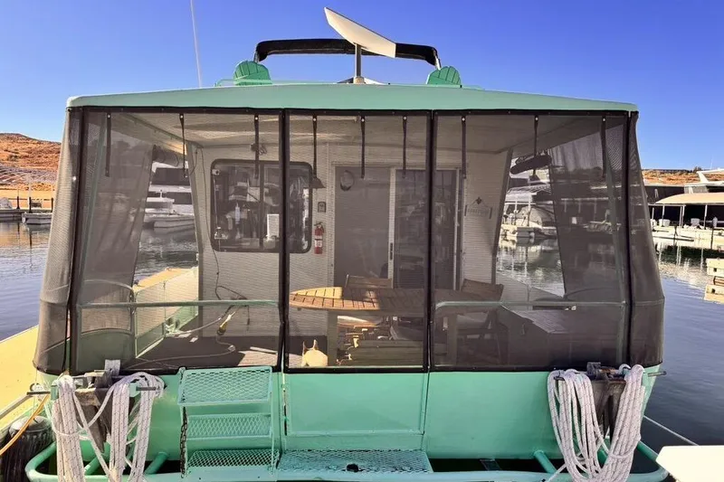 Slide: The Image of 1984 Boatel Hercules houseboat with screened deck, docked at a marina. - 4