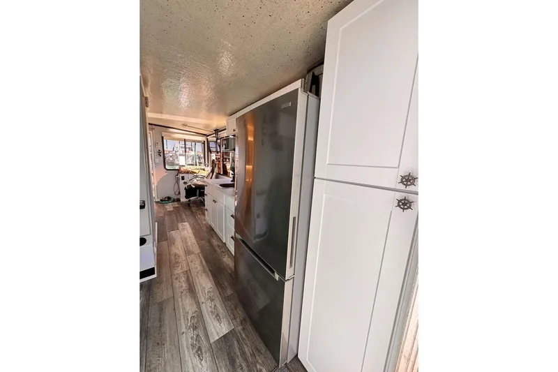 Slide: The Image of Interior of 1984 Boatel Hercules with modern kitchen, white cabinets, and wood flooring. - 9